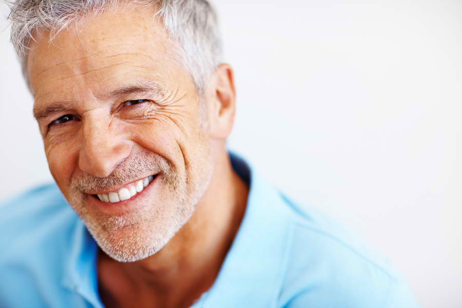 older man in blue shirt smiling with dental implant crown in knoxville