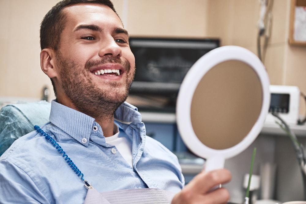 man holding mirror in dental exam chair | tooth extraction knoxville tn
