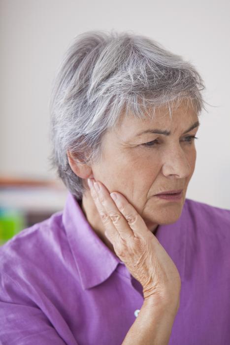 woman in purple shirt in pain holding jaw | emergency dentist knoxville tn