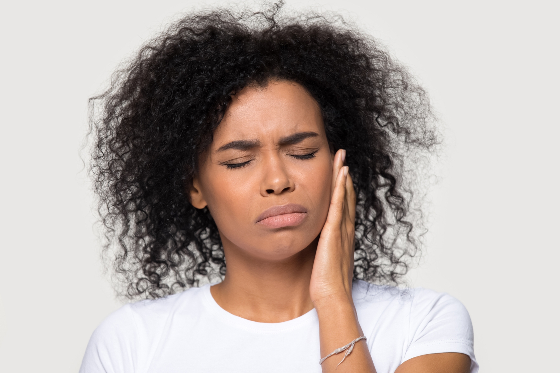 woman with curly hair and white shirt holding jaw in pain in knoxville