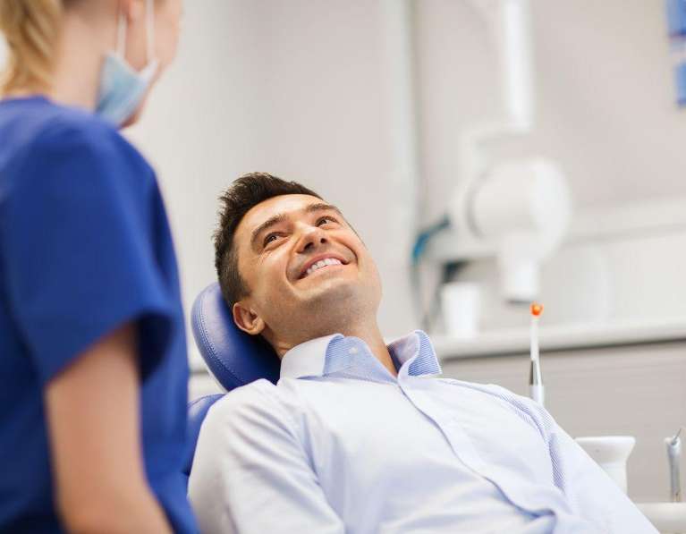 A smiling man speaking to his dentist in Knoxville