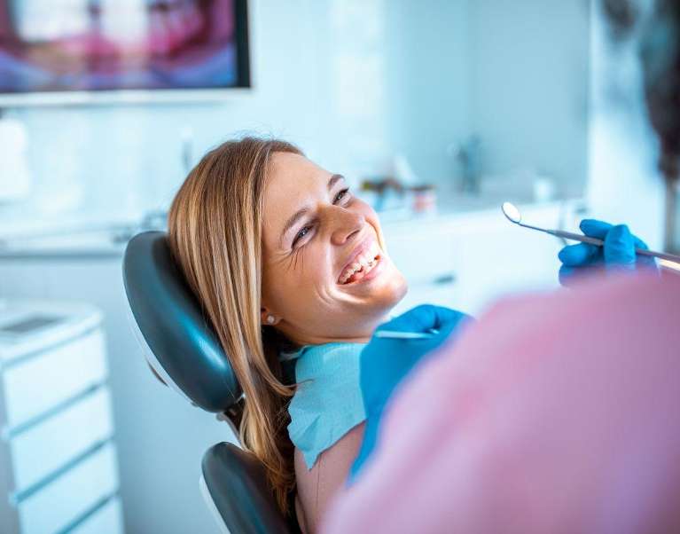 A laughing woman getting a dental exam in Knoxville