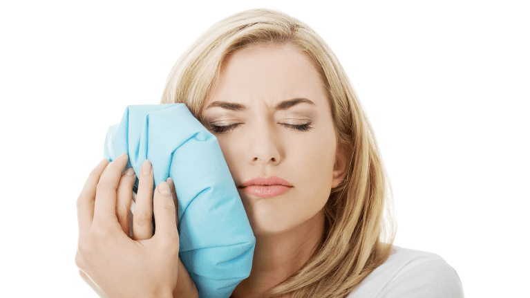A woman with a toothache holding an ice pack to her jaw